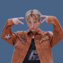 a young man wearing a brown striped jacket and a black shirt with the letter f on it