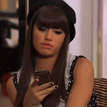 a woman with long hair wearing a black hat is looking at her phone
