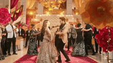 a man and a woman are dancing on a red carpet in a room surrounded by people .