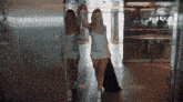 a woman in a white dress is standing in a hallway