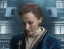 a woman in a blue jacket is looking down with her eyes closed