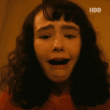 a young girl is screaming with her mouth open in a close up of her face .