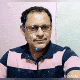 a man wearing glasses and a pink and blue striped shirt takes a selfie