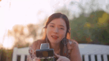 a woman is sitting on a park bench holding a polaroid camera .