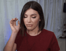 a woman in a red shirt is making a funny face with her hand