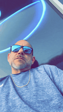 a man wearing sunglasses and a blue shirt is looking at the camera