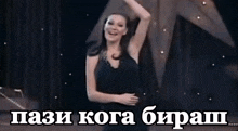 a woman in a black dress is dancing in front of a sign that says ' pa3i koga bipah '