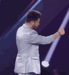 a man in a suit is standing on a stage with a microphone in his hand .