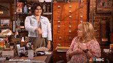 two women are sitting at a desk with the nbc logo on the bottom right