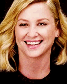 a close up of a woman 's face smiling with blonde hair .