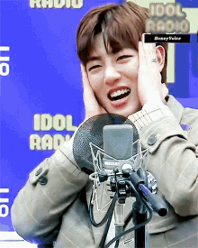 a man covering his ears with his hands in front of a microphone that says idol radio on it