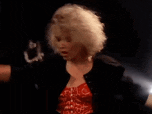 a woman in a red dress and a black jacket is dancing in a dark room .