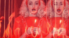 a woman in a red dress is holding two candles