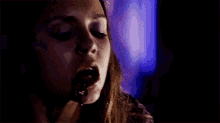 a close up of a woman 's face with blood dripping out of her mouth .