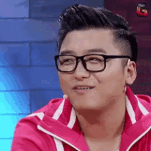 a man wearing glasses and a red jacket is smiling
