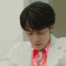 a close up of a person wearing glasses and a pink shirt .