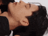a close up of a man 's neck with his eyes closed and a woman 's hand on it .