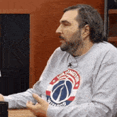 a man wearing a washington wizards sweatshirt is sitting at a table