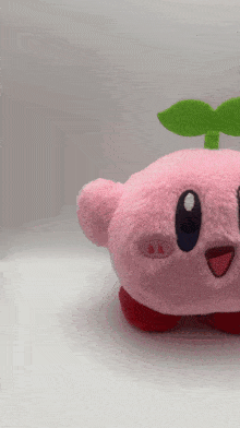 a pink kirby stuffed animal with a green leaf on top