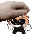 a hand is petting a cartoon character with big eyes and a hat .