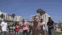 a group of people are standing around a shirtless man with a microphone in his hand