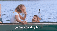 two women are sitting in a boat with the words you 're a fucking bitch above them .