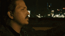 a man with a mustache is sitting in a car with his hand on his head