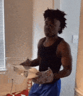 a man in a tank top and blue shorts is holding a box