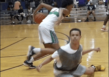 a basketball player wearing a green and white uniform with the letter t on it