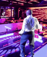a man is standing on a dance floor with tiktok written on the bottom right