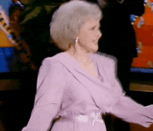 a woman in a purple dress is dancing in front of a television