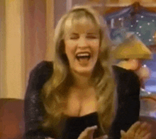 a woman is laughing while sitting on a couch with her eyes closed .