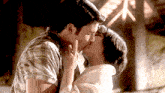a man and a woman are kissing in front of a building