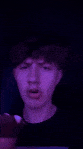 a close up of a young man 's face with a purple background .