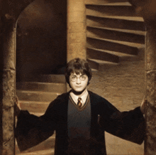 a boy in a harry potter costume stands in front of a spiral staircase