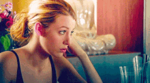 a woman in a black tank top is looking at herself in the mirror .