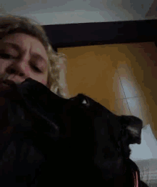 a woman is petting a black cat while looking at the camera