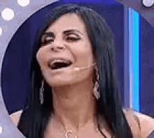 a woman with long black hair is laughing with her mouth open .