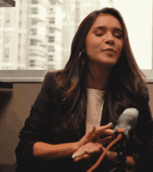 a woman sitting in front of a microphone with her eyes closed and her hands folded