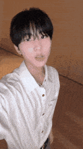 a young man in a white shirt is taking a picture of himself