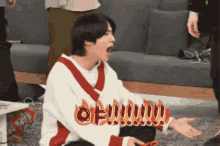 a man is sitting on the floor with his mouth open and a flame behind him that says oh !!!