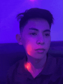 a young man is sitting in front of a purple light