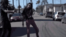 a man and a woman are dancing on a street in front of cars .