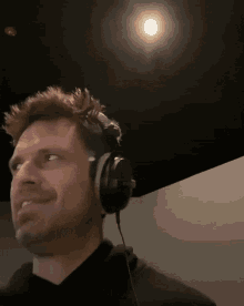 a man wearing headphones looks up at a light