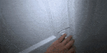 a person 's hand is reaching for a light switch on a white door