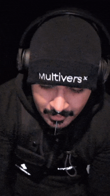 a man wearing headphones and a beanie that says multiverse