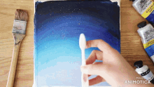 a person is holding a brush over a painting with a bottle of winsor newton acrylic paint in the background