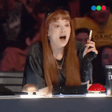 a woman with long red hair is sitting at a table holding a lighter in her hand