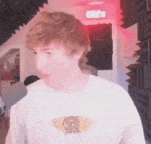 a young man wearing a white t-shirt is standing in a room with red lights .