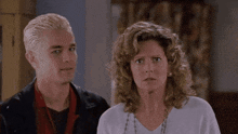a man with a spike in his hair and a woman with curly hair are standing next to each other